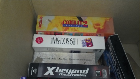 A box full of boxed software; Combat Classics 2, MS-DOS 6 Upgrade, MS-DOS 5A and X-Beyond the Final Frontier visible